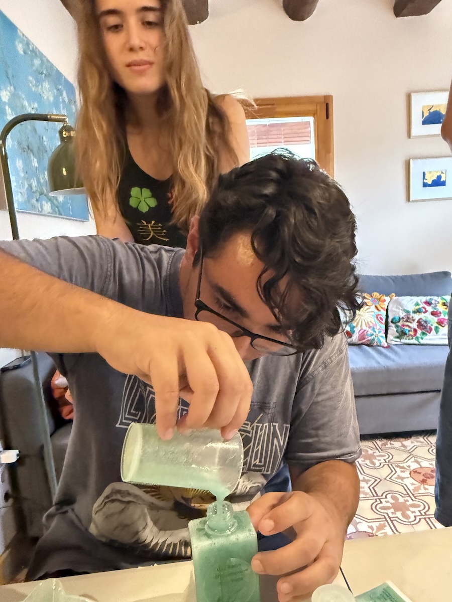 Participant abocant una preparació natural dins d'un envàs durant el taller